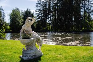 a statue of a woman sitting in a fountain in the grass at Hotel Steineweiher in Saint-Vith