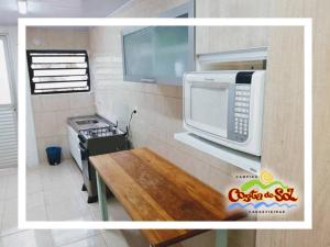 Una pequeña cocina con microondas y estufa. en Hospedagem em Canasvieiras - Pé na Areia com Vista para o Mar, en Florianópolis