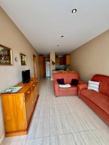 a living room with a red couch and a television at Apartamento Torreblanca III Ref 063 in Torrenostra +18 photos
