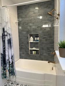 a bathroom with a tub and a black tile wall at The Cultural District Cottage in Fort Worth +14 photos