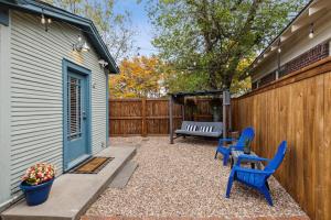 a patio with two blue chairs and a fence at The Cultural District Cottage in Fort Worth