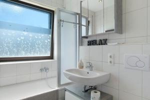 une salle de bain blanche avec un lavabo et une fenêtre dans l'établissement Ferienhaus Obergfell, 110 Qm, à Schönwald 26 autres photos