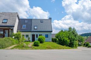 une maison blanche avec un toit gris dans une rue dans l'établissement Ferienhaus Obergfell, 110 Qm, à Schönwald
