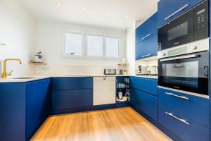a blue kitchen with white walls and wooden floors at Le Cocon de l'Oise - F2 Cosy au bord de l'eau in Saint-Ouen-lʼAumône