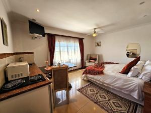 Villa Sant Andrea Boutique Luxury Villa في جوهانسبرغ: غرفة نوم بها سرير ومكتب ومطبخ