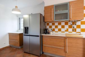 a kitchen with a stainless steel refrigerator and wooden cabinets at Villa Perogil - Charming Oasis in Tavira in Tavira