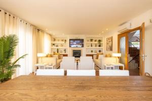 a living room with a large wooden table and white chairs at Villa Perogil - Charming Oasis in Tavira in Tavira