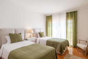 a bedroom with two beds and a chair at Villa Perogil - Charming Oasis in Tavira in Tavira