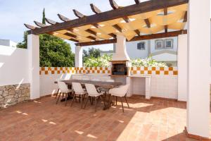 a patio with a table and chairs under a wooden pergola at Villa Perogil - Charming Oasis in Tavira in Tavira +35 photos