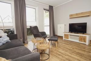 ein Wohnzimmer mit Sofa, Sesseln und Fernseher in der Unterkunft strandnahe Ferienwohnung mit eigener Terrasse - Strandhaus Mönchgut FeWo 02 in Lobbe