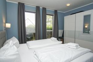 2 weiße Betten in einem Zimmer mit Fenster in der Unterkunft strandnahe Ferienwohnung mit eigener Terrasse - Strandhaus Mönchgut FeWo 02 in Lobbe