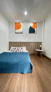 a bedroom with a blue bed and three paintings on the wall at Dago Family Stay in Bandung
