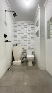 a white bathroom with a toilet and a sink at Dago Family Stay in Bandung