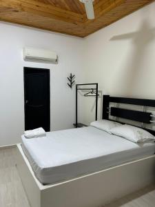ein weißes Schlafzimmer mit einem Bett mit einem schwarzen Kopfteil in der Unterkunft Hotel La Villa de Planeta Rica in Planeta Rica