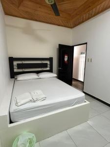 Schlafzimmer mit einem Bett mit weißer Bettwäsche und einer Holzdecke in der Unterkunft Hotel La Villa de Planeta Rica in Planeta Rica