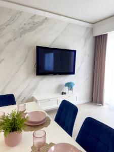 een woonkamer met een tafel en een tv aan de muur bij Apartament Portowy in Giżycko