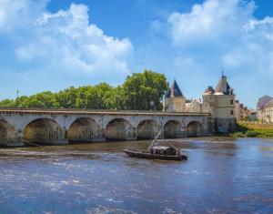 a boat on a river in front of a bridge at Studio Jozy I confort et jardin en ville 4pers I Futuroscope in Châtellerault
