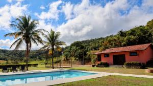 een huis met een zwembad en palmbomen bij Haras Santa Amalia - Nova União MG in União de Caeté