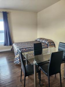 a bedroom with a glass table and chairs and a bed at Motel Rimouski in Rimouski