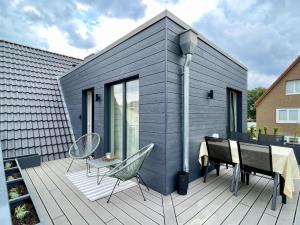 a house with a table and chairs on a deck at FRITZ21 Ferienwohnung Kellenhusen in Kellenhusen