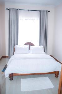 a bed with white sheets and pillows in front of a window at Luxury Peace House in Arusha