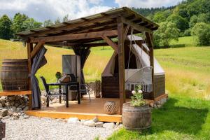a wooden gazebo with a table in a field at Glamping s piknikem u koní in Sobotín