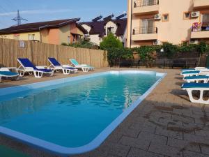 a swimming pool with chaises and chairs next to a building at Vila OK2 in Costinesti