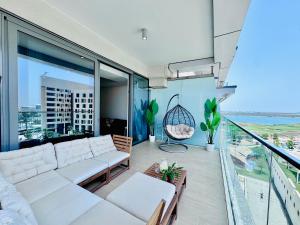 a living room with white furniture and a balcony at Circuit Views 1BR in Mayan 1 in Abu Dhabi