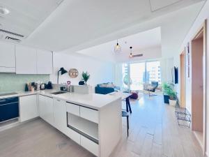 a kitchen with white cabinets and a living room at Circuit Views 1BR in Mayan 1 in Abu Dhabi