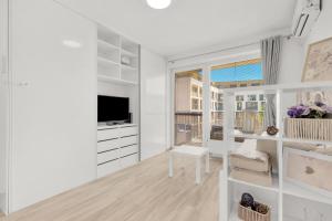 a white living room with a table and a tv at Slnecnice studio with parking and 24 hour check in in Bratislava