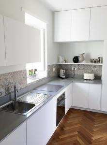 シラクーサにあるAlma Ortigiapartの白いキャビネットとシンク付きのキッチン