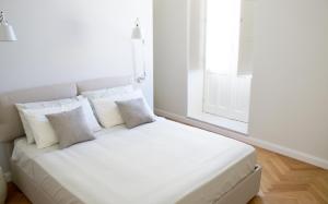 a white bed in a room with a window at Alma Ortigiapart in Siracusa