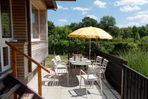a patio with a table and chairs and an umbrella at Le chalet du Ménobu in Theux
