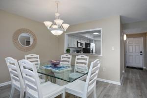 a dining room with a glass table and white chairs at Loggerhead 543 - Gorgeous Beachfront Residence at Loggerhead Cay in Sanibel