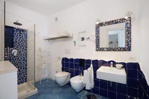 a blue and white bathroom with a toilet and a sink at Casa Il Geco Praiano in Praiano +22 photos