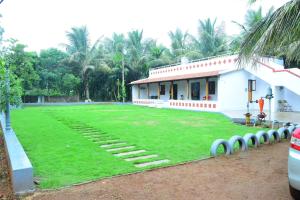 a house with a large lawn in front of it at Phalguni Farm Stay in Nanjangūd