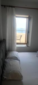 a bedroom with a bed and a window with a view of the beach at Ionian Sunset House in Piqeras +24 photos