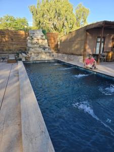 a man sitting on the edge of a swimming pool at Nueva Lodge La Estación San Pedro de Atacama in San Pedro de Atacama +5 photos