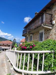 a white fence in front of a building with flowers at Casa Nieves Alojamiento Rural in Ampuero