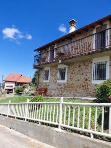an old stone house with a white fence at Casa Nieves Alojamiento Rural in Ampuero