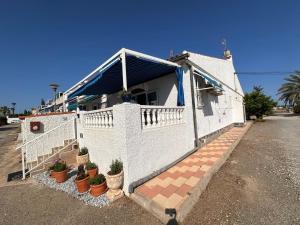 une maison blanche avec des plantes en pot devant elle dans l'établissement Peaceful Stay in Sunny Alicante, à Alicante