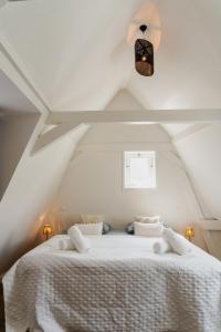 une chambre avec un lit blanc dans un grenier dans l'établissement The Rembrandt - Residence, à Amsterdam