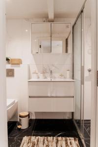 une salle de bain blanche avec lavabo et douche dans l'établissement The Rembrandt - Residence, à Amsterdam