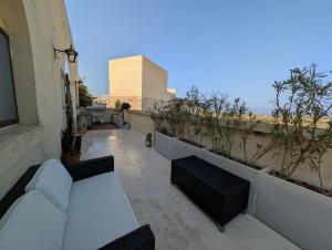 Elle comprend un balcon avec des meubles blancs et des plantes. dans l'établissement Tal Jordan Complex, à L-Għarb