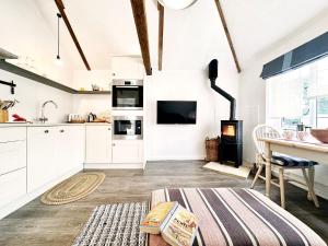 a kitchen with white cabinets and a fireplace at Spike by The Suffolk Cottage Collection in Chillesford +16 photos