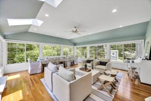 ein Wohnzimmer mit weißen Möbeln und Fenstern in der Unterkunft Spacious 7 Bed Retreat with Game Room, Deck, Yard, Half a Block from Ocean, Host Up to 22 Across 16 Beds, Gas Fireplace, Gas Grill, Ample Parking, Walk to Menauhant Beach, 24 Hr Hospitality in Falmouth