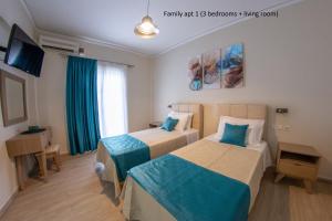 a hotel room with two beds and a television at Elaionas Holiday Home studios and apartments in Agios Stefanos