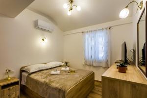 a bedroom with a bed and a tv and a window at Kuća Ružica in Omiš