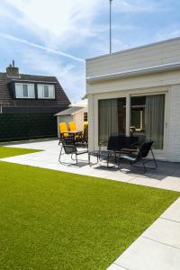 een patio met stoelen en een tafel naast een gebouw bij -Casa Nova- nabij het meer, duinen en restaurants in Noordwijkerhout