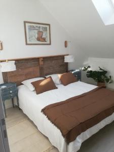 a bedroom with a large white bed with brown pillows at La mansarde in Nozay